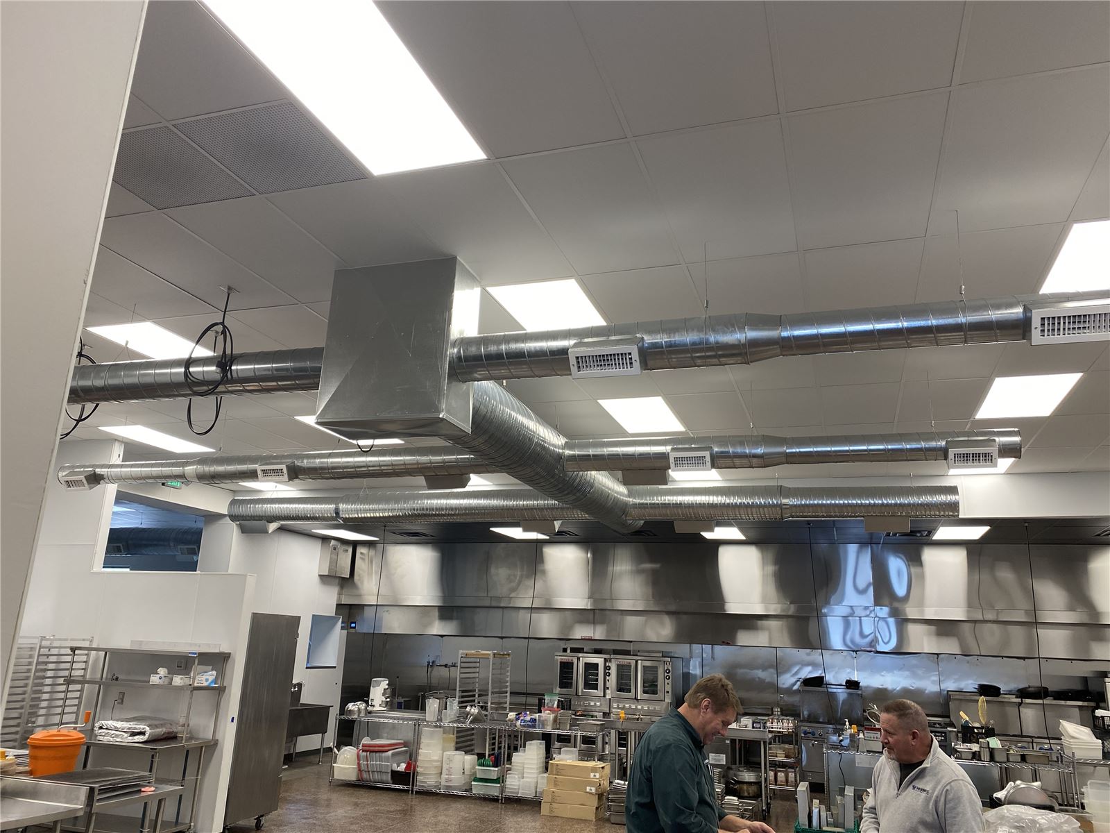 Commercial kitchen with stainless exhaust hoods and cooking line