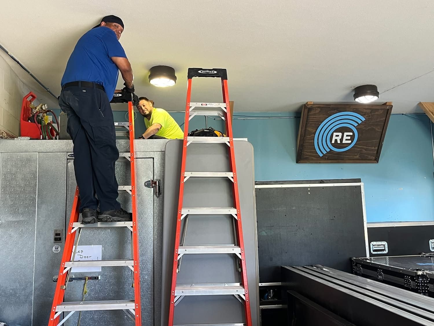 Valley technicians on ladders servicing a walk-in refrigeration system